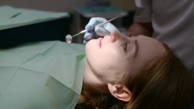Modern tıp merkezinde dişçi ve hasta. Doktor hastanede genç bir kadının dişlerini tedavi ediyor. Pratisyen, ortodontistlerden ya da protez tedavisinden önce hastayı muayene eder. Hijyen ve dişler sağlıklı.