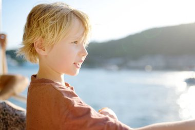 Sarışın reşit olmayan çocuk denizde tekne ya da feribot ile seyahat ediyor. Okyanus ya da denizde aile tatilleri. Çocuklu aileler için yaz tatili. Çocuk tatilde.