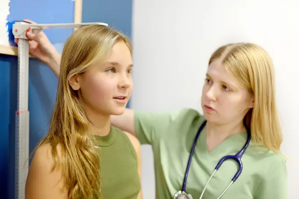Kvindelig Læge Måling Teenage Pige Højde Skolepige Patient Børnelæge Udnævnelse Royaltyfrie stock-fotos