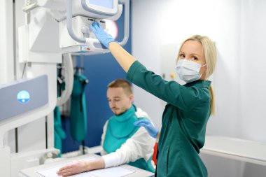Modern klinikteki röntgen odasında kırık el röntgeni çektiren genç bir adam. Hasta kurşun önlük takıyor. İnsanların tıbbi muayenesi