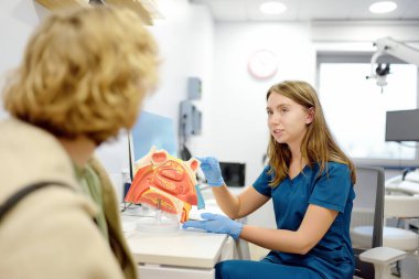 Otolargolog randevuda hastaya danışıyor. Profesyonel KBB doktoru insan burnunun bir modelini gösteriyor. Burun iltihabının tedavisi. Burun burnunun kıvrımı.