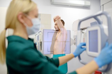 Kadın radyolog modern kliniğin röntgen odasında hastanın akciğerlerinin röntgenini çekiyor. Doktor florografi yapıyor. İnsanların tıbbi muayenesi tüberkülozun dünyaya yayılmasına engel olmaktır.