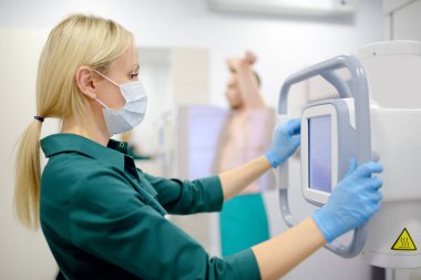 Kadın radyolog modern kliniğin röntgen odasında hastanın akciğerlerinin röntgenini çekiyor. Doktor florografi yapıyor. İnsanların tıbbi muayenesi tüberkülozun dünyaya yayılmasına engel olmaktır.