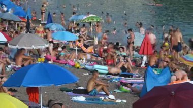 Sıcak bir yaz gününde insanlarla dolu bir plajın hızlandırılmış videosu. Tatil sezonu. Adriyatik Denizi - Karadağ, Rafailovici - 1 Ağustos 2023 