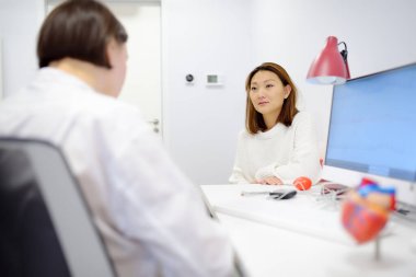 Hastanın randevusu sırasında bir kardiyolog. Doktor kalp çalışmasındaki sapmaları açıklıyor. Kardiyoloji danışma ve tedavi. Dünya Kalp Günü