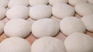 Yerel bir fırının mutfağındaki masada pişmeye hazır bir yığın hamur parçası. Zeytin ciabatta kurusıkı büyük bir fırının önüne serilmiş. Yerel ekmek üretimi