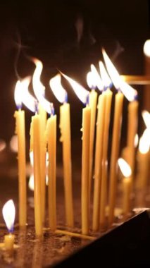 Kilisede yanan bir grup ince mum. Cemaatten biri, Ortodoks veya Katolik kiliselerindeki bir kilise ayininden sonra mum yakar. Hıristiyan Noel veya Paskalya