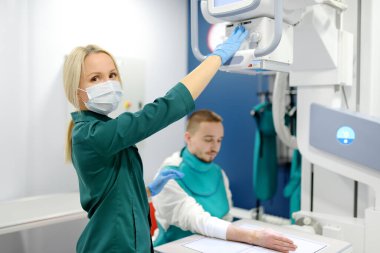 Modern klinikteki röntgen odasında kırık el röntgeni çektiren genç bir adam. Hasta kurşun önlük takıyor. İnsanların tıbbi muayenesi