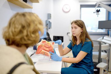 Otolargolog randevuda hastaya danışıyor. Profesyonel KBB doktoru insan burnunun bir modelini gösteriyor. Burun iltihabının tedavisi. Burun burnunun kıvrımı.