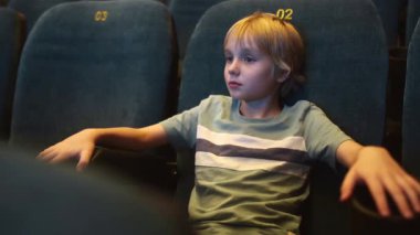 Sinemada ya da tiyatroda gösteri bekleyen tatlı bir çocuk. Çocuklu bir aile için eğlence. Çocuklar için kültürel etkinlik.