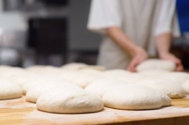 Yerel bir fırının mutfağındaki masada pişmeye hazır bir yığın hamur parçası. Zeytin ciabatta kurusıkı büyük bir fırının önüne serilmiş. Yerel ekmek üretimi. Ciabatta yapımı