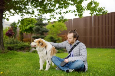 Genç sahibi bahar günü büyük köpeğiyle halka açık parkta yürüyor. Hayvan bakımı. Köpek gezdiren kişi.