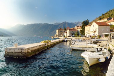 Perast, Karadağ - 9 Şubat 2025: Karadağ 'ın antik Perast kentinin nefes kesici panoramik günbatımı manzarası. Kırmızı çatıları ve arka planında görkemli dağları olan eski bir ortaçağ kasabası.
