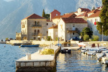 Perast, Karadağ - 9 Şubat 2025: Eski Perast kasabasının manzarası. Antik çan kulesi ve merdivenler güneşli bir günde denize iniyor. Perast, Karadağ 'da popüler bir turizm kasabası