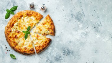 Italian pizza four cheeses with stretching cheese and basil on a light concrete background. Top view with copy space.