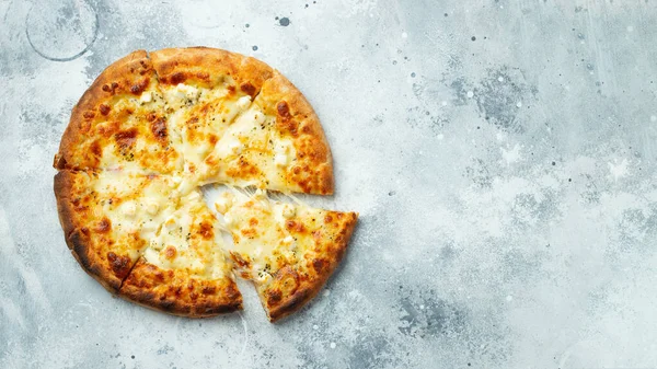 Italian pizza four cheeses with stretching cheese and basil on a light concrete background. Top view with copy space.