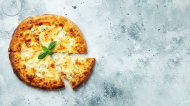 Italian pizza four cheeses with stretching cheese and basil on a light concrete background. Top view with copy space.