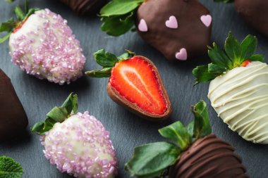 Koyu arkaplanda çikolata kaplı çilekler..