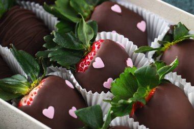 Koyu arkaplanda çikolata kaplı çilekler. Sevgililer Günü için bir kutuda lezzetli çilekler.