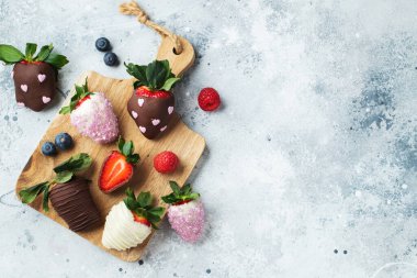 Açık arkaplanda çikolata kaplı çilekler var. Kopyalama alanı olan üst görünüm.