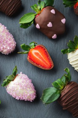 Koyu arkaplanda çikolata kaplı çilekler..