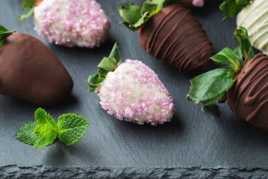 Koyu arkaplanda çikolata kaplı çilekler..