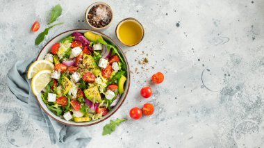 Farklı yaprak ve sebzelerden oluşan lezzetli ve sağlıklı yeşil salata. Hafif beton arka planda tohum ve peynir karışımı. Boşluğun bir kopyasıyla en üstteki görünüm.