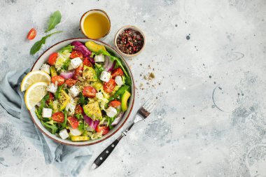 Farklı yaprak ve sebzelerden oluşan lezzetli ve sağlıklı yeşil salata. Hafif beton arka planda tohum ve peynir karışımı. Boşluğun bir kopyasıyla en üstteki görünüm.