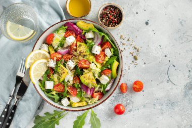 Farklı yaprak ve sebzelerden oluşan lezzetli ve sağlıklı yeşil salata. Hafif beton arka planda tohum ve peynir karışımı. Boşluğun bir kopyasıyla en üstteki görünüm.