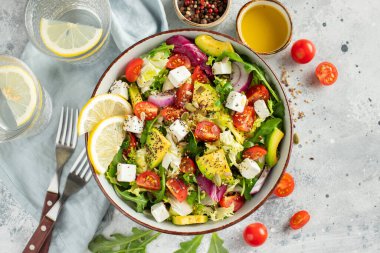 Farklı yaprak ve sebzelerden oluşan lezzetli ve sağlıklı yeşil salata. Hafif beton arka planda tohum ve peynir karışımı. Boşluğun bir kopyasıyla en üstteki görünüm.