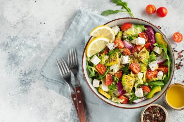 Farklı yaprak ve sebzelerden oluşan lezzetli ve sağlıklı yeşil salata. Hafif beton arka planda tohum ve peynir karışımı. Boşluğun bir kopyasıyla en üstteki görünüm.