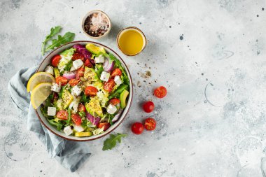 Farklı yaprak ve sebzelerden oluşan lezzetli ve sağlıklı yeşil salata. Hafif beton arka planda tohum ve peynir karışımı. Boşluğun bir kopyasıyla en üstteki görünüm.