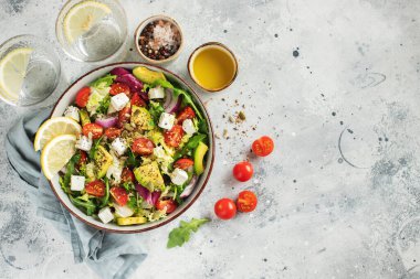 Farklı yaprak ve sebzelerden oluşan lezzetli ve sağlıklı yeşil salata. Hafif beton arka planda tohum ve peynir karışımı. Boşluğun bir kopyasıyla en üstteki görünüm.