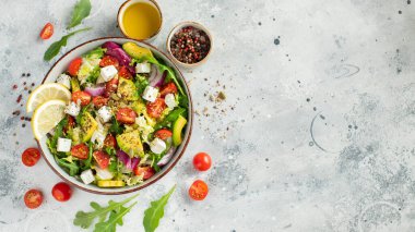 Farklı yaprak ve sebzelerden oluşan lezzetli ve sağlıklı yeşil salata. Hafif beton arka planda tohum ve peynir karışımı. Boşluğun bir kopyasıyla en üstteki görünüm.