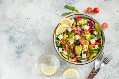 Farklı yaprak ve sebzelerden oluşan lezzetli ve sağlıklı yeşil salata. Hafif beton arka planda tohum ve peynir karışımı. Boşluğun bir kopyasıyla en üstteki görünüm.