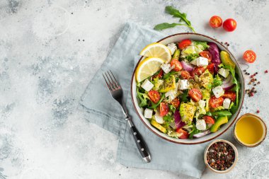 Farklı yaprak ve sebzelerden oluşan lezzetli ve sağlıklı yeşil salata. Hafif beton arka planda tohum ve peynir karışımı. Boşluğun bir kopyasıyla en üstteki görünüm.
