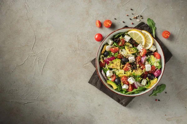 Farklı yaprak ve sebzelerden oluşan lezzetli ve sağlıklı yeşil salata. Koyu beton arka planda tohum ve peynir karışımı. Boşluğun bir kopyasıyla en üstteki görünüm.