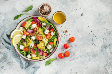 Farklı yaprak ve sebzelerden oluşan lezzetli ve sağlıklı yeşil salata. Hafif beton arka planda tohum ve peynir karışımı. Boşluğun bir kopyasıyla en üstteki görünüm.
