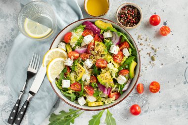 Farklı yaprak ve sebzelerden oluşan lezzetli ve sağlıklı yeşil salata. Hafif beton arka planda tohum ve peynir karışımı. Boşluğun bir kopyasıyla en üstteki görünüm.