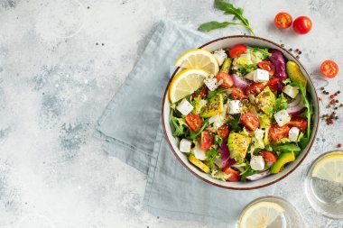 Farklı yaprak ve sebzelerden oluşan lezzetli ve sağlıklı yeşil salata. Hafif beton arka planda tohum ve peynir karışımı. Boşluğun bir kopyasıyla en üstteki görünüm.