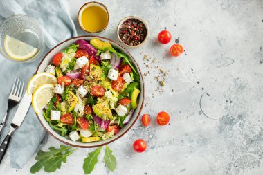 Farklı yaprak ve sebzelerden oluşan lezzetli ve sağlıklı yeşil salata. Hafif beton arka planda tohum ve peynir karışımı. Boşluğun bir kopyasıyla en üstteki görünüm.