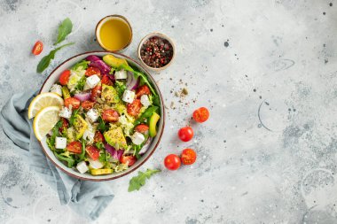 Farklı yaprak ve sebzelerden oluşan lezzetli ve sağlıklı yeşil salata. Hafif beton arka planda tohum ve peynir karışımı. Boşluğun bir kopyasıyla en üstteki görünüm.