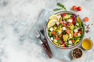 Farklı yaprak ve sebzelerden oluşan lezzetli ve sağlıklı yeşil salata. Hafif beton arka planda tohum ve peynir karışımı. Boşluğun bir kopyasıyla en üstteki görünüm.
