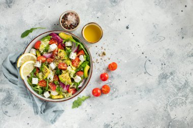 Farklı yaprak ve sebzelerden oluşan lezzetli ve sağlıklı yeşil salata. Hafif beton arka planda tohum ve peynir karışımı. Boşluğun bir kopyasıyla en üstteki görünüm.