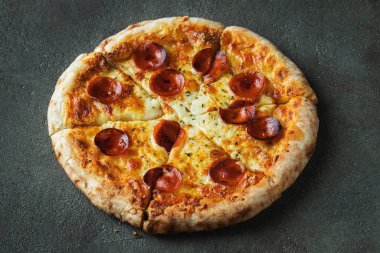 Bir dilim peynirli sıcak İtalyan pizzası. Siyah arka planda pizza sosisi..