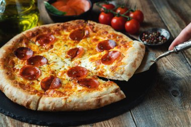 Bir dilim peynirli sıcak İtalyan pizzası. Koyu ahşap arka planda pizza sosisi..