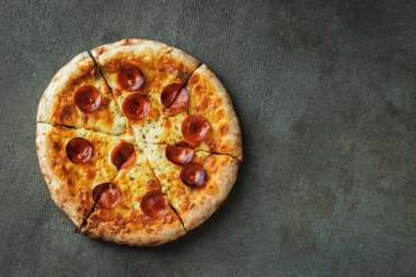 Bir dilim peynirli sıcak İtalyan pizzası. Siyah arka planda pizza pepperonisi. Kopyalama alanı olan üst görünüm.