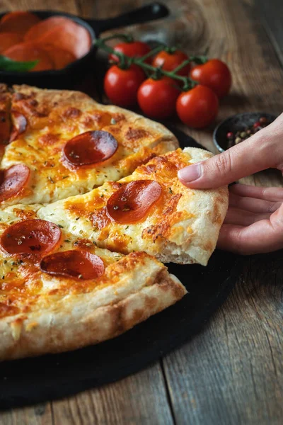 Bir dilim peynirli sıcak İtalyan pizzası. Koyu ahşap arka planda pizza sosisi..