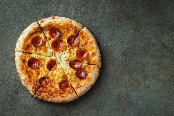 Bir dilim peynirli sıcak İtalyan pizzası. Siyah arka planda pizza pepperonisi. Kopyalama alanı olan üst görünüm.