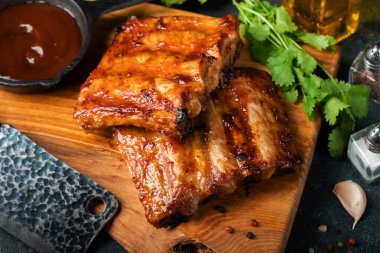 Baharatlı, ızgara pirzola. Barbekü, acı biber ve taze domatesle servis edilir. Eski bir ahşap kesim tahtasının üzerinde.